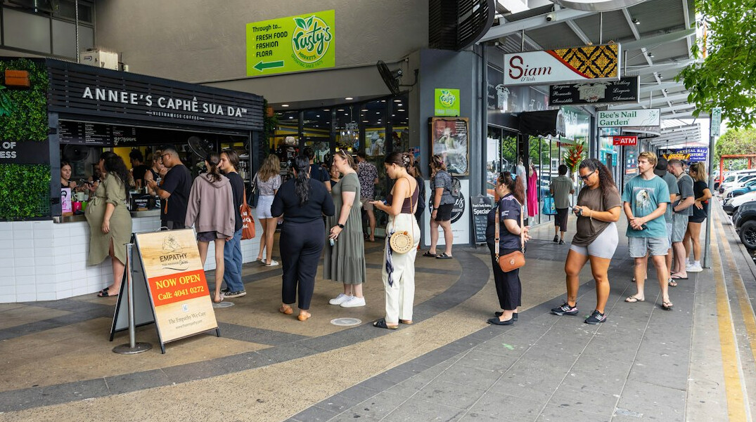 People standing in a queue outside a shop in the city